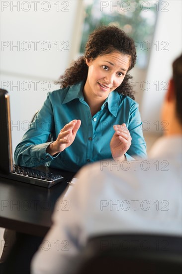 Woman interviewing man at desk.