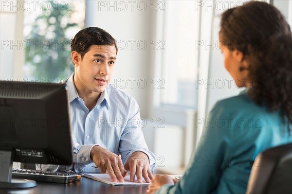 Man and woman talking at desk during job interview.