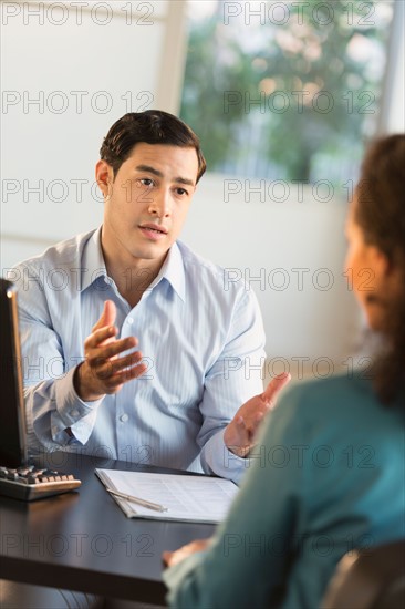 Man and woman talking at desk during job interview.