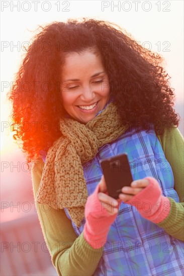 Portrait of mid adult woman using mobile phone at sunset.