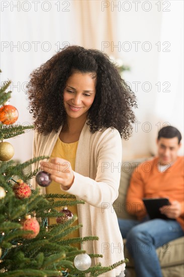 Woman decorating Christmas tree.