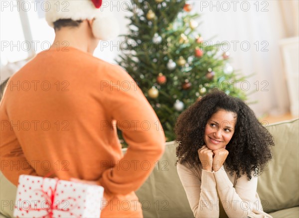 Man holding Christmas gift for woman.