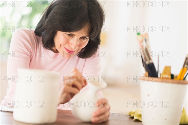 Senior woman painting handmade pottery.