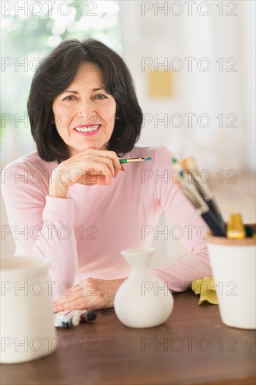 Senior woman painting handmade pottery.