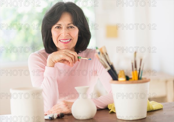 Senior woman painting handmade pottery.