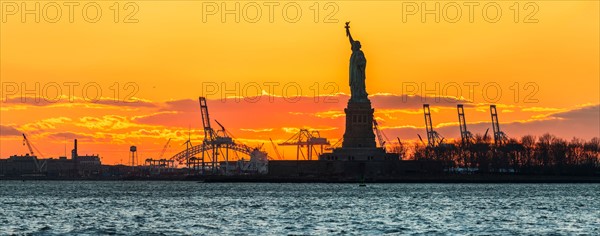 Silhouette of Statue of Liberty at sunset.