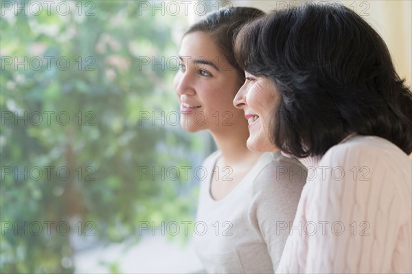 Portrait of grandmother and granddaughter (16-17) looking through window.