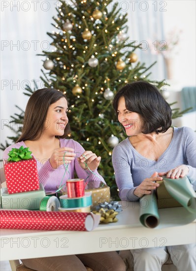 Grandmother and granddaughter (16-17) wrapping christmas gifts.