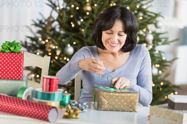 Senior woman wrapping christmas gifts.