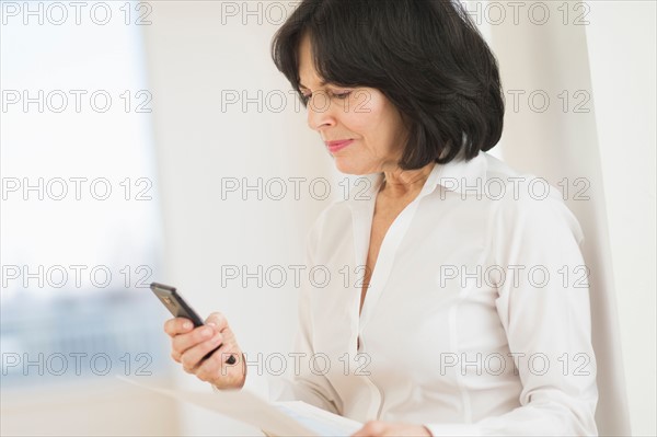 Portrait of senior businesswoman texting on mobile.