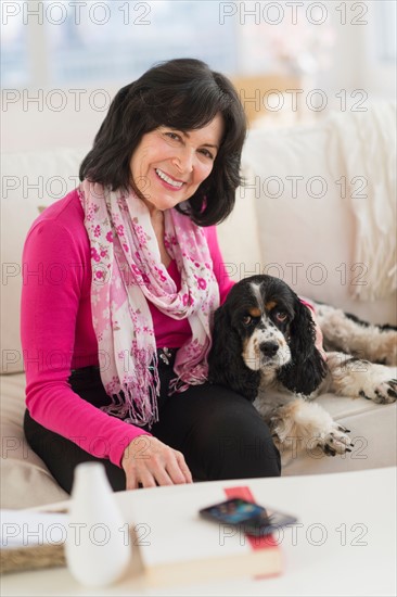 Portrait of senior woman sitting on sofa with her dog.