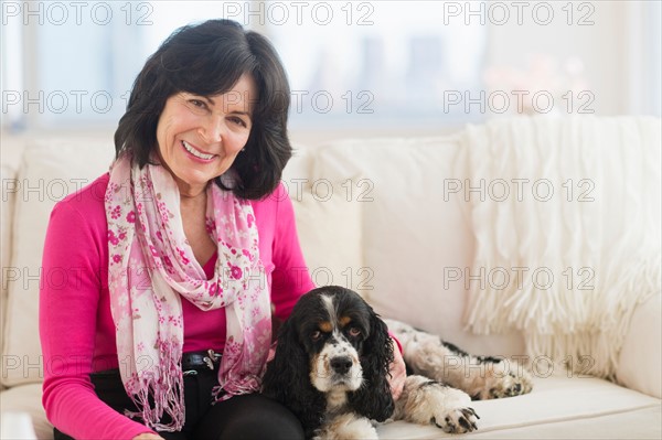Portrait of senior woman sitting on sofa with her dog.