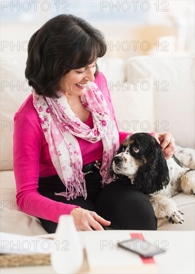 Portrait of senior woman sitting on sofa with her dog.