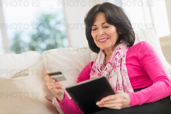 Senior woman with digital tablet and credit card.