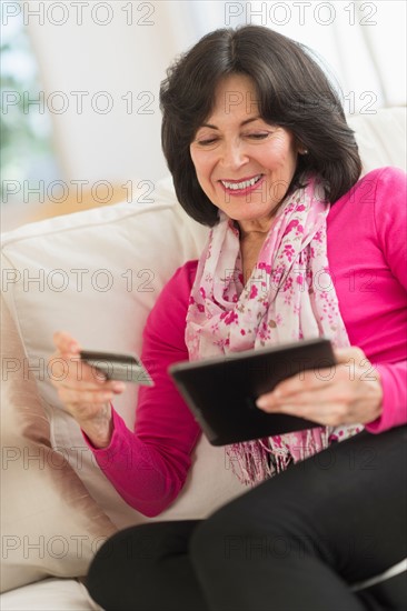 Senior woman with digital tablet and credit card.