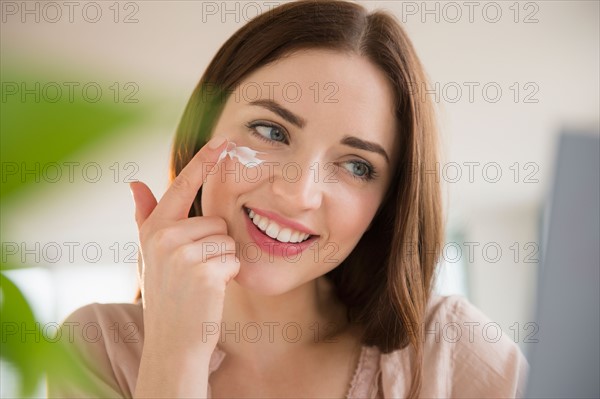 Young woman applying face cream