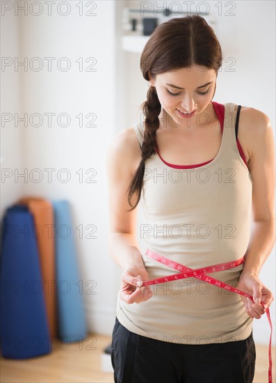 Young woman measuring waist