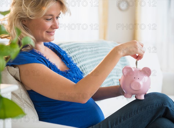 Portrait of pregnant woman with piggy bank