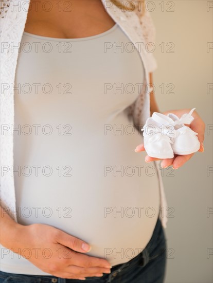 Pregnant woman holding baby shoes