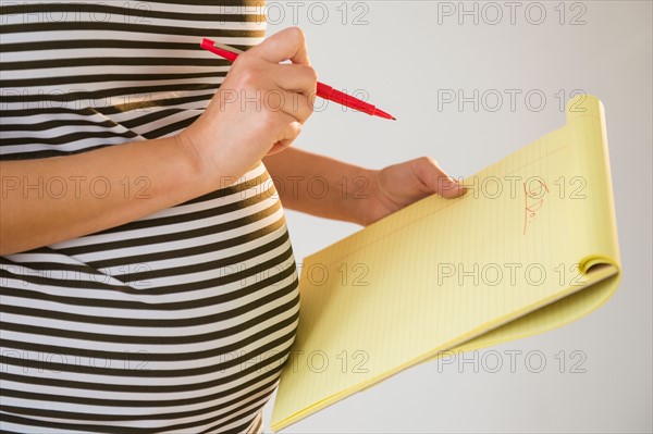 Pregnant woman holding pencil and notebook