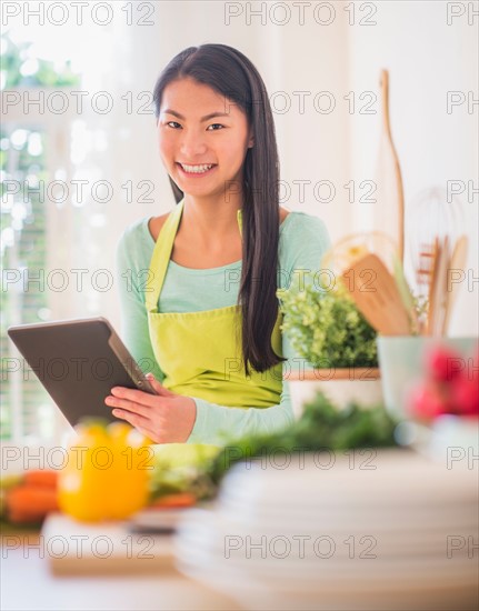 Teenage girl using digital tablet in kitchen