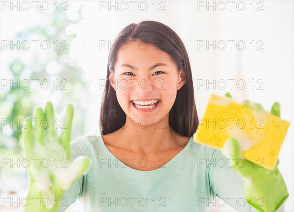 Teenage girl wearing rubber gloves and holding sponge