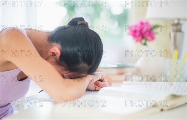 Side view of teenage girl ( 16-17 years ) with her head on table