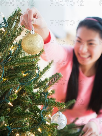Teenage girl ( 16-17 years) decorating Christmas tree