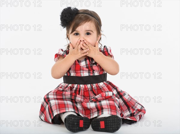 Portrait of Baby girl ( 6-11 months) wearing plaid dress with hands on mouth