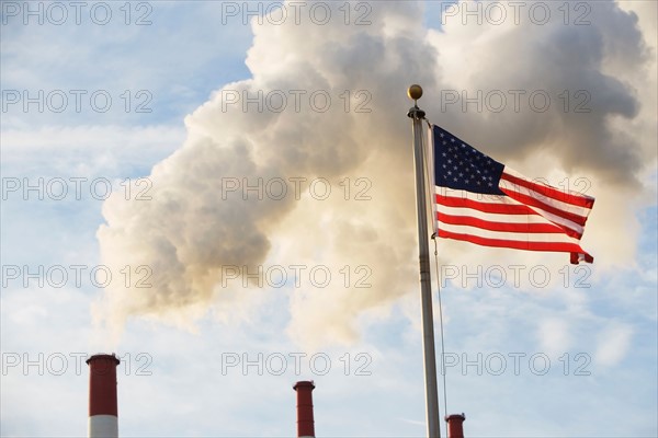 American flag in front of smoke stacks