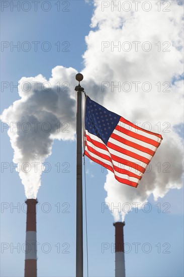 American flag in front of smoke stacks