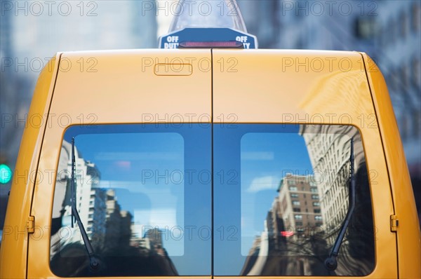 Reflection in rear window of yellow taxi