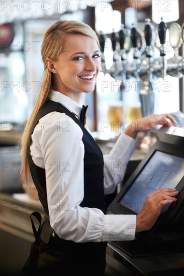 Young waitress using computer at restaurant counter