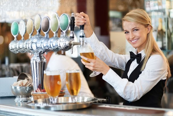 Female bartender pouring beer