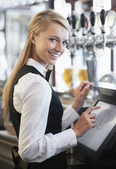 Young waitress using computer at restaurant counter