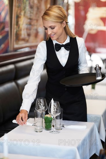 Portrait of young waitress setting table