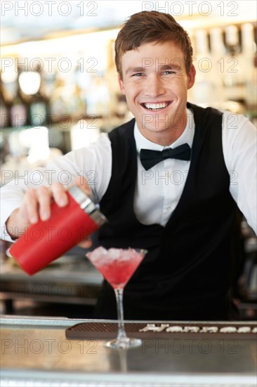 Young bartender pouring cocktail