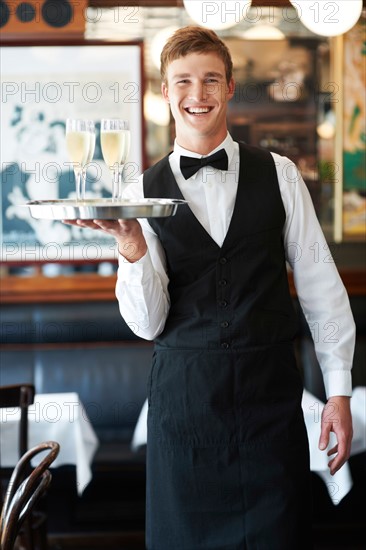 Portrait of waiter holding champagne flutes on tray