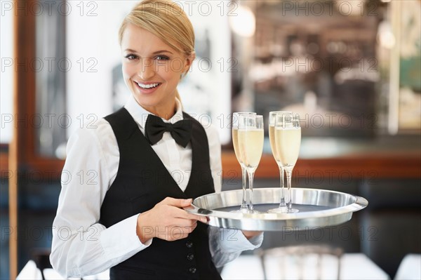 Portrait of waitress holding champagne flutes on tray