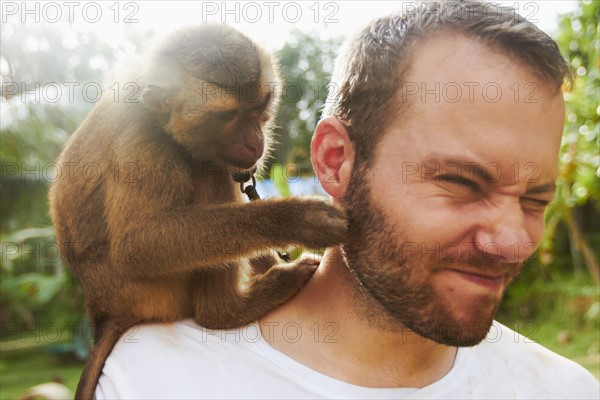Portrait of adult man with macaque monkey sitting on his shoulder