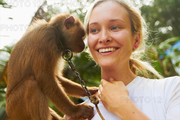 Portrait of young woman holding macaque monkey