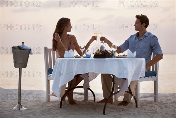 Couple eating at table on tropical beach