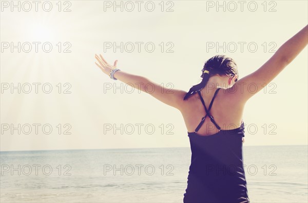 Rear view of girl (8-9) standing with arms raised