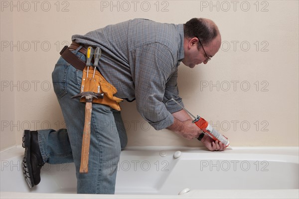 Man with Caulk Gun working in bathroom