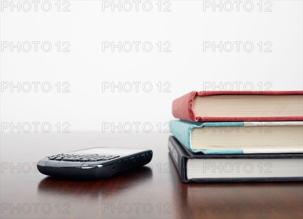 Mobile phone beside stack of books