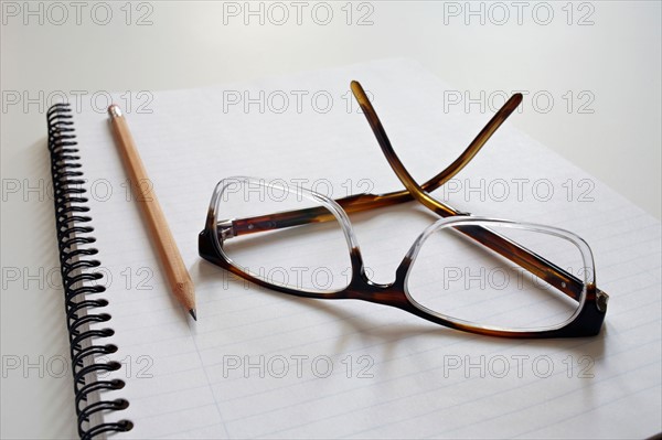 Empty note pad with pencil and spectacles