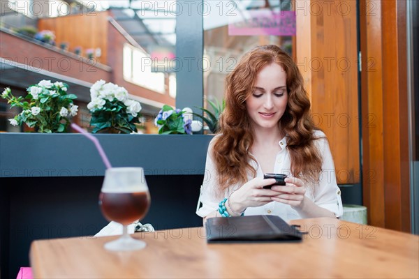 Elegant woman in cafe using mobile phone