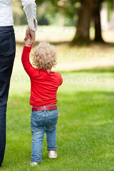 Rear view of girl (2-3) walking with her mother