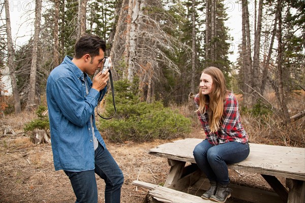 Young man photographing his girlfriend in non-urban scene