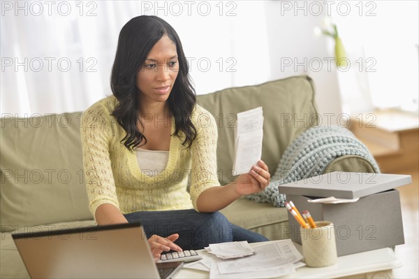 Woman using laptop and going through bills.